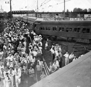 Black and white photograph depicting a crowd gathering to observe a train wreck.